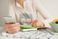 Woman making notes in notepad with healthy food on table Royalty Free Stock Photo