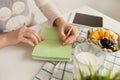 Woman making notes in notepad with healthy food on table Royalty Free Stock Photo