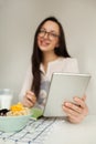 Woman making notes with tablet and healthy food on table Royalty Free Stock Photo