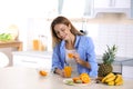 Woman making orange juice at table in kitchen Royalty Free Stock Photo