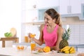 Woman making orange juice at table in kitchen Royalty Free Stock Photo