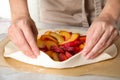 Woman making peach pie at kitchen table