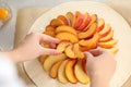 Woman making peach pie at table, closeup