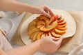 Woman making peach pie at table, closeup