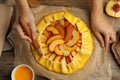 Woman making peach pie at table, top view