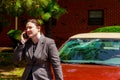 Woman making a phone call by the damaged windshield after a car accident Royalty Free Stock Photo