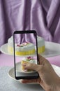 Woman making photo of fondant decorated celebration cake with her phone on purple Royalty Free Stock Photo