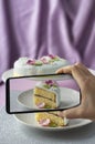 Woman making photo of fondant decorated celebration cake with her phone on purple Royalty Free Stock Photo