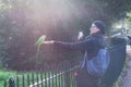A woman making photo of a green parakeet at Hyde Park in London on a sunny day. Royalty Free Stock Photo
