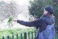 A woman making photo of a green parakeet at Hyde Park in London on a sunny day. Royalty Free Stock Photo