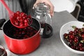 Woman making pickled cherries at table indoors, closeup