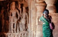 Woman making picture by iphone inside the 6th century Hindu temple with caves. Carvings in ancient places, India