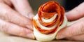 woman is making rose-shaped pepperoni snack. pastry with salami. homemade puff pastry ready to bake.