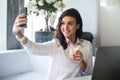 Woman making self portrait with a cell phone camera in restaurant taking picture on smart phone. Royalty Free Stock Photo