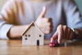 A woman making and showing thumbs up hand sign while holding car figure model and wooden house model Royalty Free Stock Photo