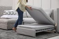 Woman making sleeping place for guest in living room, closeup. Convertible sofa