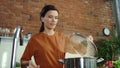 Woman making soup in kitchen. Girl adding salt to boiling pot.