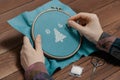 Woman making stitch on canvas and embroidering pattern