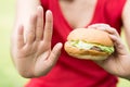 Woman making stop sign with hamburger