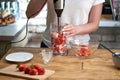 Woman making strawberry smoothie. Healthy eating, cooking and summer refreshment concepts