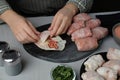 Woman making stuffed cabbage rolls at grey table, closeup