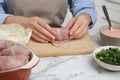 Woman making stuffed cabbage rolls at white marble table, closeup