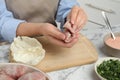 Woman making stuffed cabbage rolls at white marble table, closeup