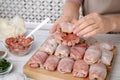 Woman making stuffed cabbage rolls at white wooden table, closeup