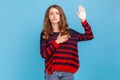 Woman making swearing gesture and holding arm on chest, taking oath, pledging allegiance. Royalty Free Stock Photo