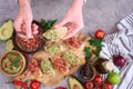 Woman making tasty salsa and guacamole bruschetta snacks at domestic kitchen