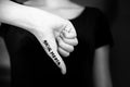 Black and white close-up of woman`s hand making thumbs down gesture with words social media written on hand