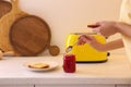 Woman making toasts with jam at table in kitchen, closeup. Weekend morning