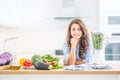 Woman making vegetable soup or smoothies with blender in her kitchen. Young happy woman preparing healthy drink with spinach