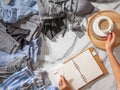 Woman is making daily to do list and schedule on notebook the organization of wardrobe in a closet.