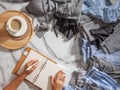 Woman is making daily to do list and schedule on notebook the organization of wardrobe in a closet.