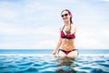 Woman making wooing gesture at edge of infinity pool