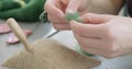 Woman making wool art doll toy at table close up. Female sitting and creating ooak doll at home. Needle Felted Handmade