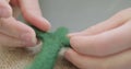 Woman making wool art doll toy at table close up. Female sitting and creating ooak doll at home. Needle Felted Handmade