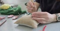 Woman making wool art doll toy at table close up. Female sitting and creating ooak doll at home. Needle Felted Handmade