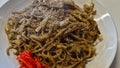 woman is making yakisoba on a hot stove where water, raw ingredients and eggs are placed on a hot plate