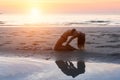 Woman making yoga exercises on the beach in the setting sun. Royalty Free Stock Photo