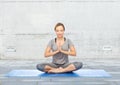 Woman making yoga meditation in lotus pose on mat