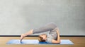 Woman making yoga in plow pose on mat