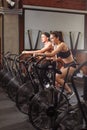 Woman and man biking in gym, exercising legs doing cardio workout cycling bikes Royalty Free Stock Photo