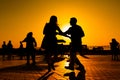 Woman and man couple silhouettes dancing against warm sunset orange sky