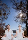 Woman and man doing yoga in front of a lake and mountains Royalty Free Stock Photo