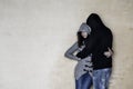 Woman and a man dressed with grey and black clothes, both wearing blue jeans, hugging, leaning on a textured wall Royalty Free Stock Photo