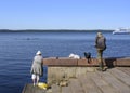 A woman and a man fishing on the embankment of Lake Onega near the pier with tourist ships