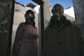 a woman and a man in a gas mask staying in destroyed building