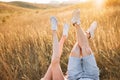 Woman and man having fun outdoors. Loving hipster couple are lying in the grass and lifting their legs in sneakers up in Royalty Free Stock Photo